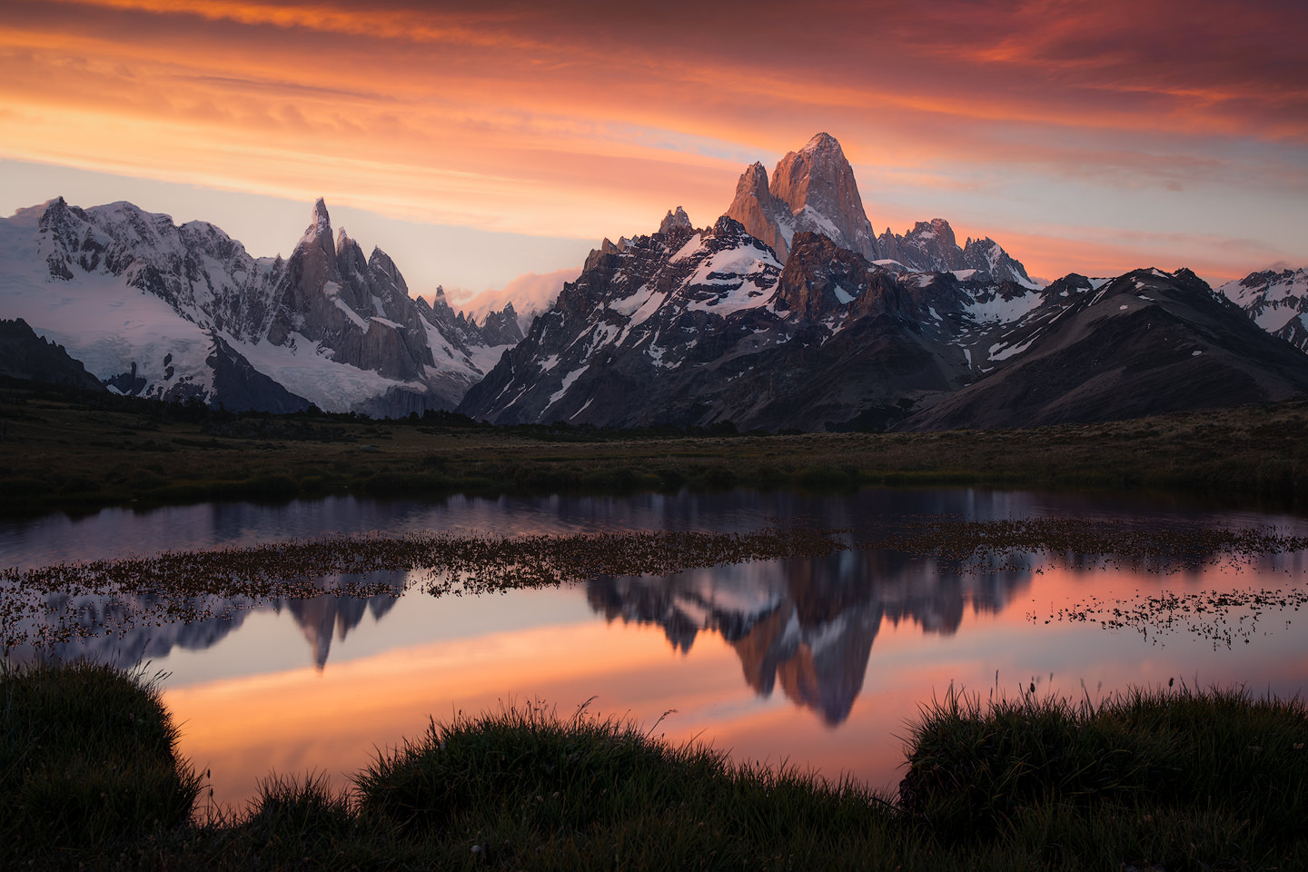 Cerro Torre and Fitz Roy reflected in an infinity pool during an intense sunset.